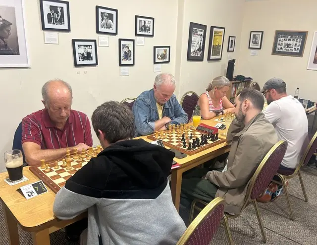 Boards 7 and 8 with framed grandmaster portraits and posters on the wall behind